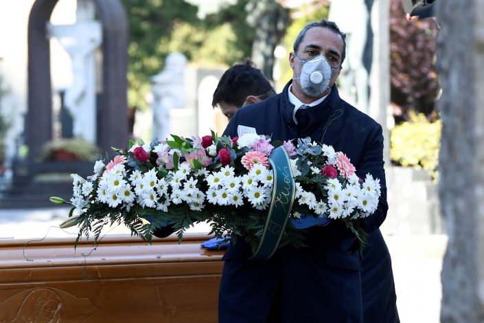 Trabalhadores dos cemitérios e das agências funerárias, com máscaras protectoras, durante o funeral de uma pessoa morta devido ao coronavírus COVID-19, em Bérgamo, Itália, a 16 de Março de 2020. O número de mortes provocadas pelo COVID-19, em Itália, ultrapassou hoje as registadas na China desde o início do ano, apesar de este país ter uma população 24 vezes superior à da Itália 